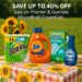 A vibrant promotional image featuring household products in a cozy summer laundry room setting. The scene includes bottles and packaging from brands like Tide and Swiffer, a rustic wooden shelf, sunflowers in a vase by a sunny window, and folded towels. The offer text reads “Up to 40% Off Procter & Gamble Household Essentials – July 28, 2025” with the website URL “dailydealbusters.com” clearly displayed at the bottom.