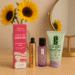 Flat lay of GrandeLASH-MD Lash Enhancing Serum, Clinique Take The Day Off Makeup Remover, and Clinique All About Clean Liquid Facial Soap on a vanity table with sunflowers. Summer BOGO beauty deal promotion.