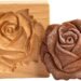 Wooden cookie mold pressing a rose-shaped design into cookie dough on a festive fall kitchen counter