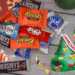 Festive arrangement of assorted Christmas candy bags displayed on a fall-to-holiday themed backdrop.