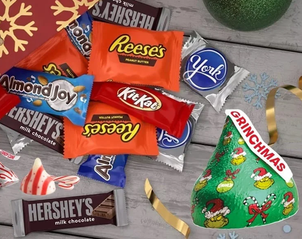Festive arrangement of assorted Christmas candy bags displayed on a fall-to-holiday themed backdrop.