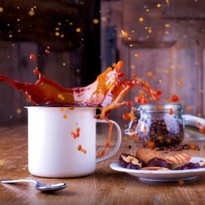 Assorted packaged snacks displayed on a table with a cup of coffee and a dynamic coffee splash in the background