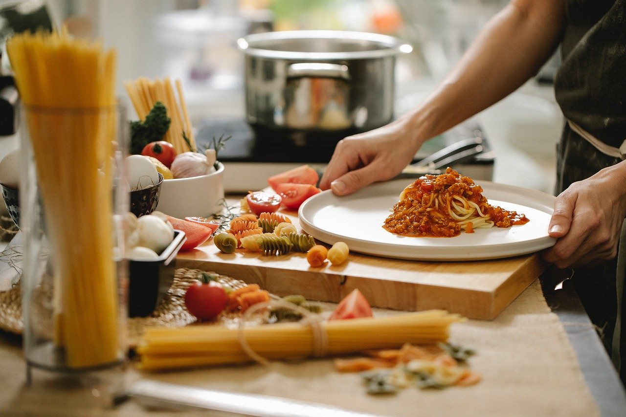 Close-up kitchen scene showing spaghetti pasta preparation with ingredients for Italian cooking.Name
