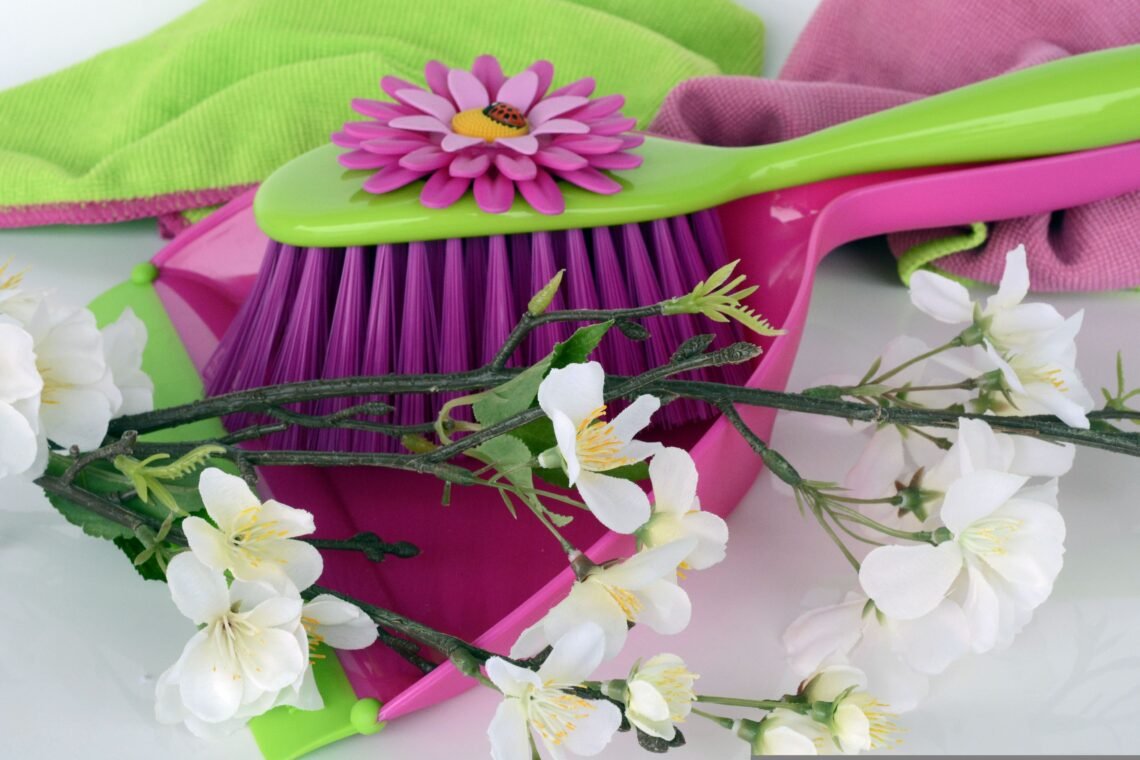 A bright spring-themed cleaning setup featuring floor care products with soft blue skies, light clouds, and subtle cherry blossom accents for a clean seasonal feel