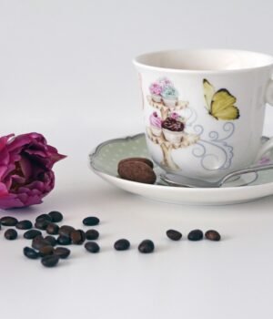 A cozy spring-themed coffee setup featuring coffee mugs and pods with soft blue skies, light clouds, and subtle cherry blossom accents for a calm seasonal feel
