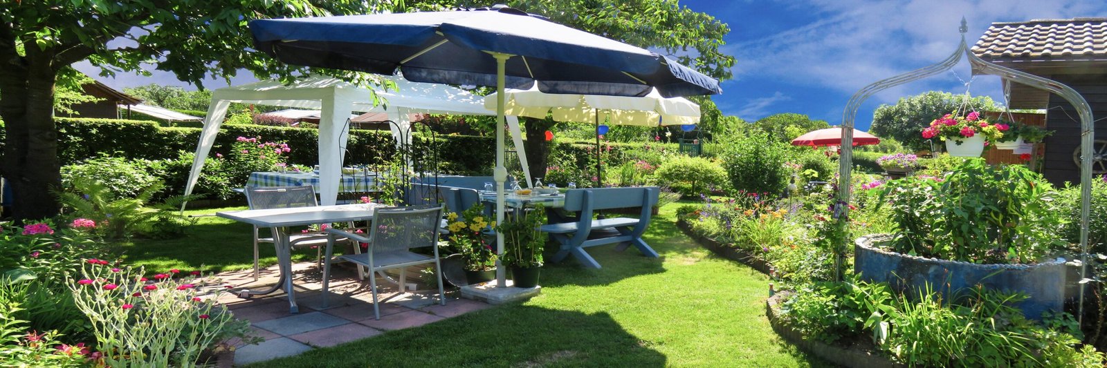 A bright spring and summer-themed snack setup featuring beverages, chips, cereals, and pantry foods with soft blue skies, light clouds, and subtle cherry blossom accents for a cheerful seasonal feel