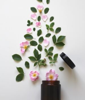 A soft spring-themed beauty setup featuring skincare and natural wellness products with light clouds, soft blue skies, and subtle cherry blossom accents for a calm seasonal feel