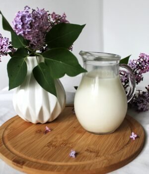 A soft spring-themed pantry beverage setup featuring milk cartons with light clouds, soft blue skies, and subtle cherry blossom accents for a calm seasonal feel