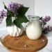 A soft spring-themed pantry beverage setup featuring milk cartons with light clouds, soft blue skies, and subtle cherry blossom accents for a calm seasonal feel