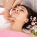 A bright spring-inspired wellness setup featuring skincare and beauty products with soft blue skies, light clouds, and subtle cherry blossom accents for a calm seasonal feel