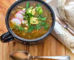 Bowl of chicken verde soup with bright green salsa verde broth and toppings.