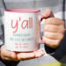 Funny white ceramic mug with a pink handle and interior featuring the phrase “You All Y’all Gonna Make Me Lose My Mind.”