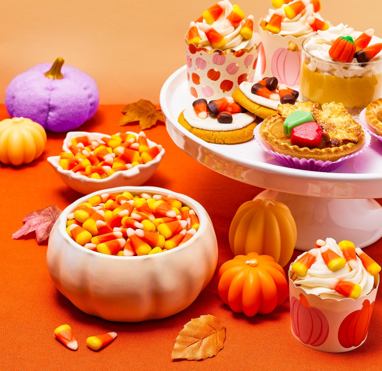 Brach's candy corn packages displayed together with pieces of classic candy corn.